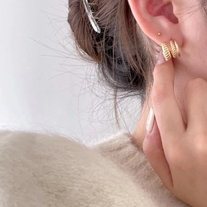 Three-piece set of minimalist golden geometric stud earrings worn by a model in a cozy style
