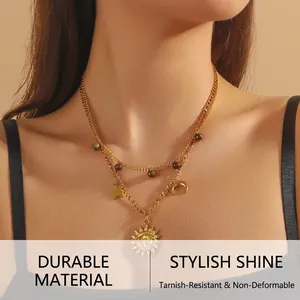 Detail of double-layer gold necklace with sun, moon, star pendants and tiger eye beads