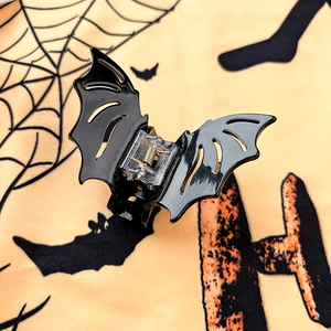 Close-up of black bat-shaped hair claw clip with glossy finish and clear spring detail