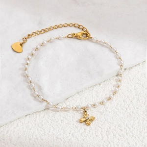 Macro shot of gold cross pendant with crystal inlay on a beaded pearl bracelet