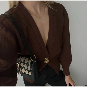 Detail of V-neck brown cardigan featuring vertical rib texture and a gold hammered button