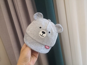 Detail of grey striped baby cap featuring 3D bear ears and soft cotton texture