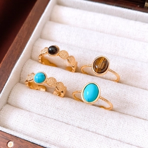 Macro detail of 18k gold plated tiger eye and turquoise rings in a jewelry box