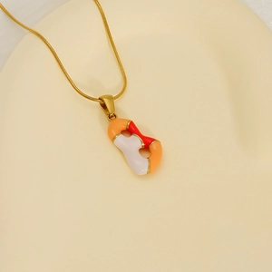 Détail macro du collier en acier doré avec pendentif en émail orange, blanc et rouge vif