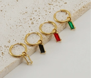 Detail van gouden oorringen met groene, rode, zwarte en heldere vierkante zirkoonhangers