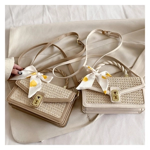 Detail of straw woven bags in khaki and beige with silk scarves and metal locks
