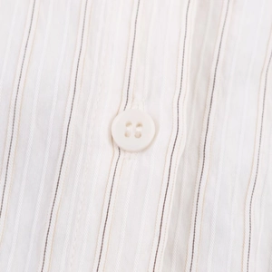 Detailed macro view of white vertical pinstripe fabric and a four-hole button on the shirt