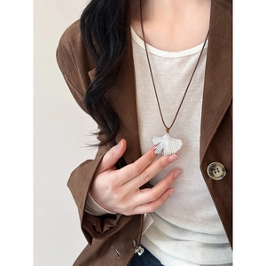 Silver ginkgo leaf pendant necklace with brown leather cord on a female model