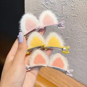 Close-up of three plush cat ear hair clips in pink and yellow for little girls