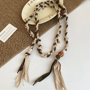 Detail of woven boho belt with resin beads and metallic accents on artistic background