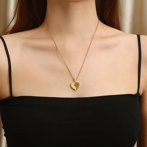 Collier cœur doré élégant avec motifs ajourés et cristaux porté par un mannequin