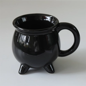 Detailed view of the three-legged black ceramic cauldron mug with a smooth glossy finish