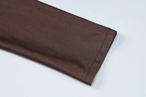 Gros plan sur la texture du tissu marron lisse et les coutures précises du poignet