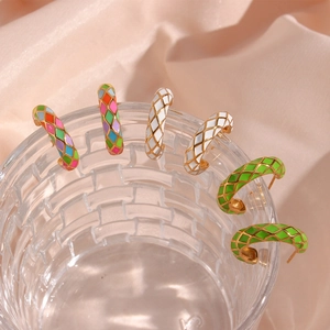 Macro view of retro colorful checkered enamel earrings on a glass edge with satin backdrop