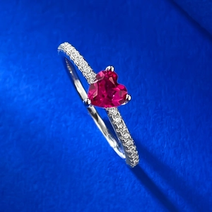 Macro shot of heart-cut red gemstone ring with micro-pave diamonds on silver band