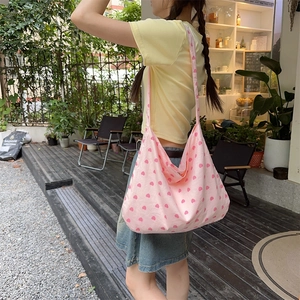 Detailed shot of a pink canvas tote bag with red heart patterns worn at an outdoor cafe