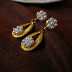Detailed close-up of vintage flower pearl earrings with golden matte drop design