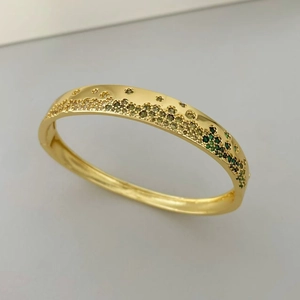 Détail d'un bracelet en or poli avec des zircons micro-pavés verts et cristallins