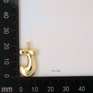Golden balloon letter J pendant showing 4.55g weight and dimensions on a ruler