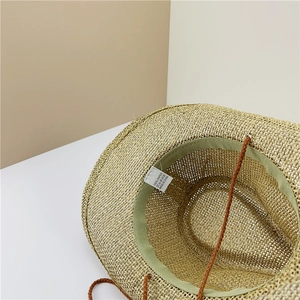 Internal detail of woven straw hat featuring 100% paper material and adjustable chin strap