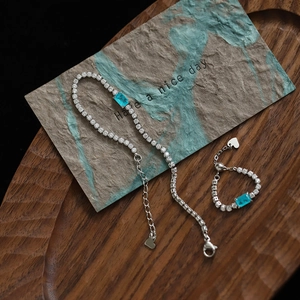 Close-up of blue gemstone bracelet and ring set on an artistic wooden tray display