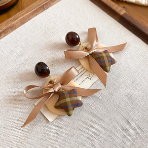 Détail de boucles d'oreilles nœud en tissu vintage avec étoile à carreaux sur fond beige