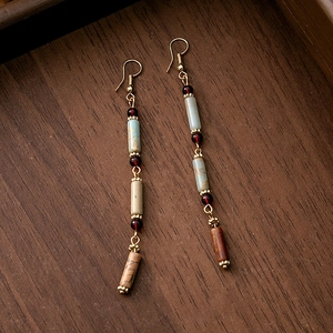 Macro detail of Chinese vintage tassel earrings with hollow beads on wooden background