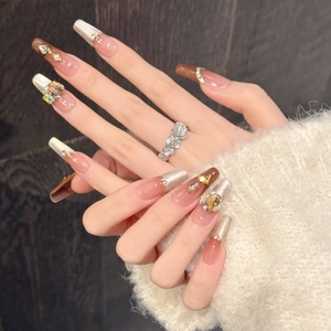 Détail de faux ongles ballerine longs avec paillettes œil de chat marron et strass chic