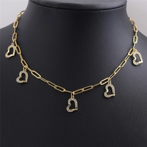 Détail du collier chaîne trombone doré avec cinq pendentifs cœurs sertis de zircons sur un buste
