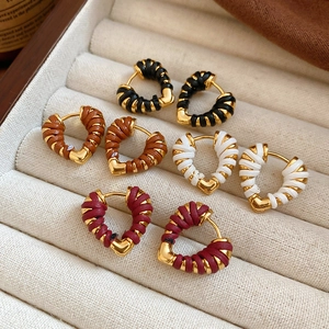 Détail de créoles en forme de cœur tissées en noir, marron, blanc et bordeaux avec or 18k