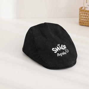 Close-up of Smile Again embroidery on a black denim beret hat with detailed texture