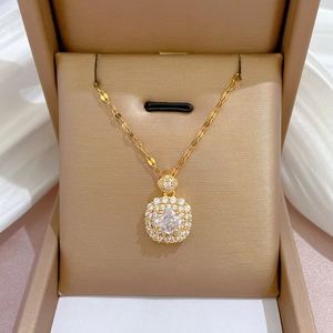 Gros plan d'un pendentif carré doré avec micro-pavé de cristaux dans son écrin de luxe