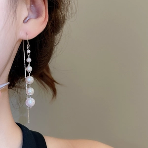 Close-up of elegant silver drop earrings featuring five graduated pearls worn by a model