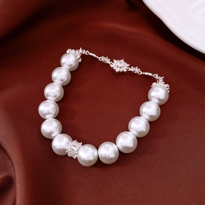 Detailed close-up of pearl bracelet with floral zircon pendant on luxury silk background