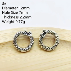 Detailed view of silver Ouroboros metal spacer bead with 12mm diameter on wood tray