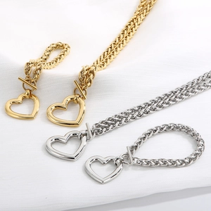 Detailed view of gold and silver heart pendant necklaces with T-bar clasps on white fabric