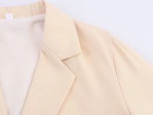 Detail of the elegant notched lapel and woven texture on a beige commuter suit jacket