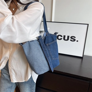 Retro denim patchwork bucket bag shown on shoulder in a modern minimalist interior setting