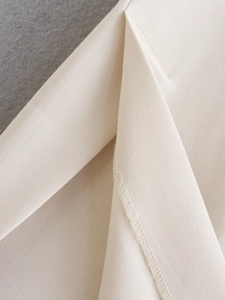 Detailed macro view of beige fabric texture with high-quality overlock stitching edge