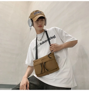 Close-up of brown nylon messenger bag with double front pockets on male model
