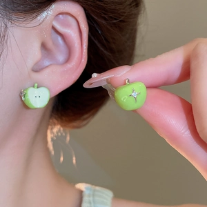Detail showing a pair of green apple-shaped stud earrings with sparkling star zircon gems