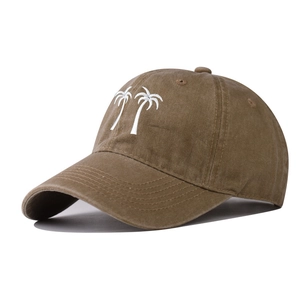 Detailed view of white palm tree embroidery on a washed brown cotton baseball cap
