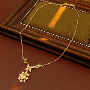 Détail d'un collier doré vintage avec pierre jaune et nœud sur un cadre en bois sombre