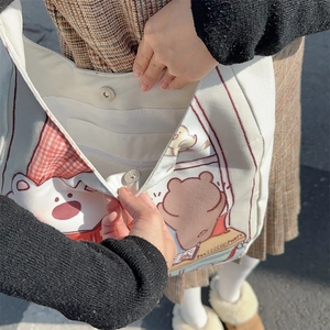 Detail of canvas tote bag showing magnetic buckle and inner zipper pocket for storage