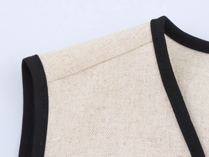 Dettaglio del bordo a contrasto sulla spalla di un abito in lino beige senza maniche
