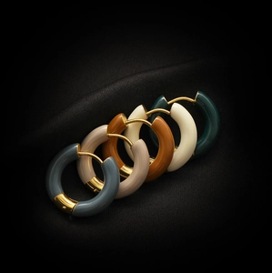 Détail de créoles colorées en émail plaqué or 18 carats sur satin noir chic