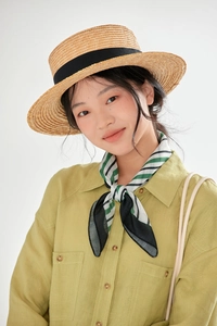 Close-up of a floral cotton linen scarf tied on a model with a straw hat and green linen shirt