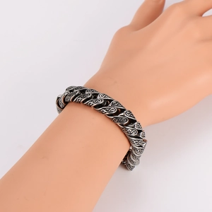 Bracciale largo vintage in acciaio inossidabile con motivi floreali su mano modello