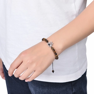 Close-up of tiger eye bead bracelet with silver lotus projection stone on a wrist