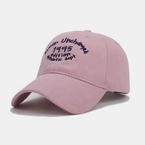 Detail of vintage pink cotton baseball cap featuring blue athletic embroidery and curved brim